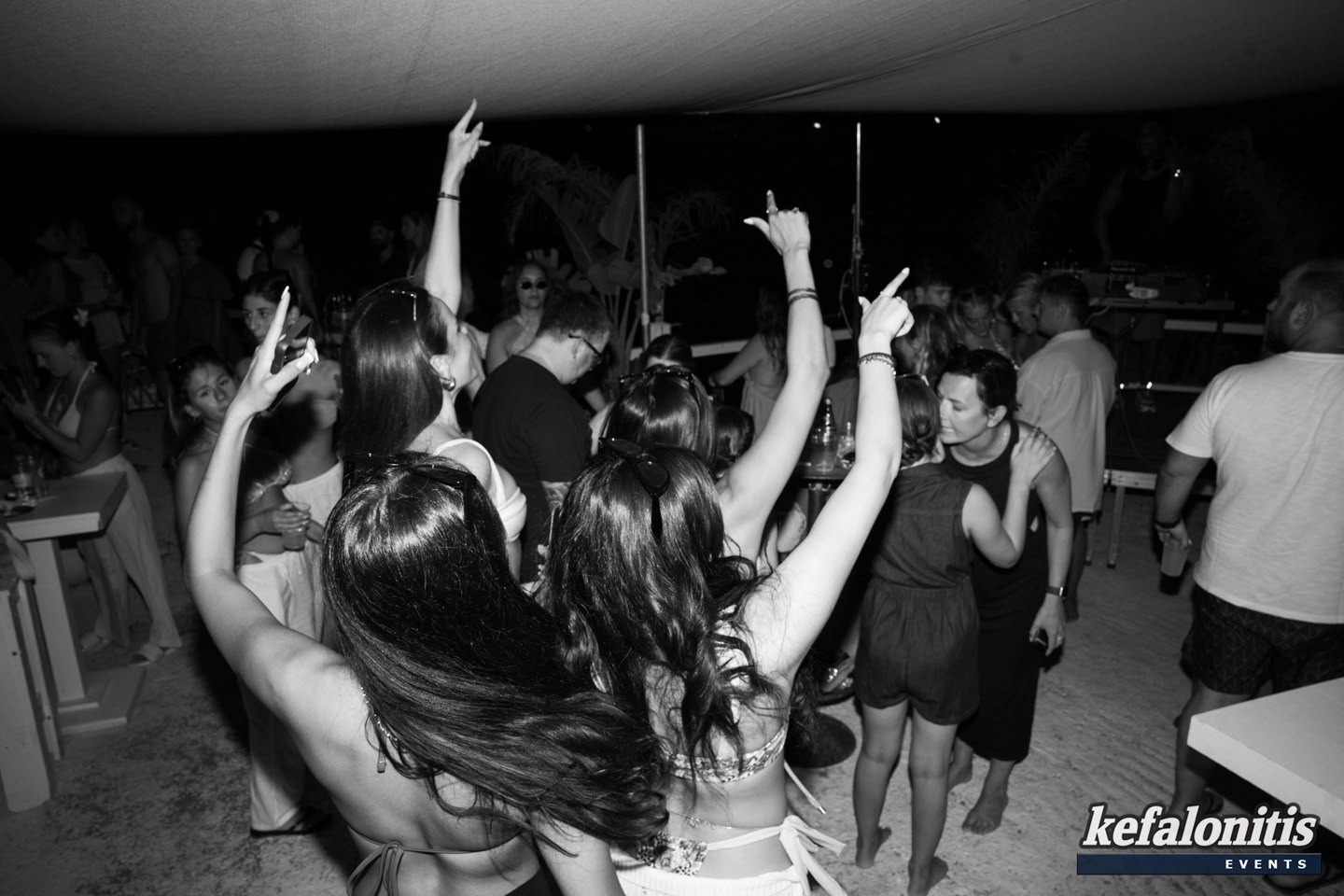 Crowd dancing with hands up on the sand